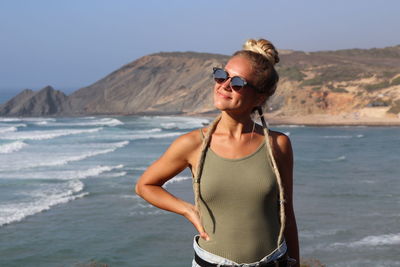 Young woman wearing sunglasses standing at beach