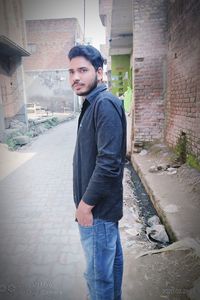 Portrait of young man standing against building