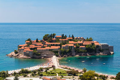 Buildings by sea against blue sky