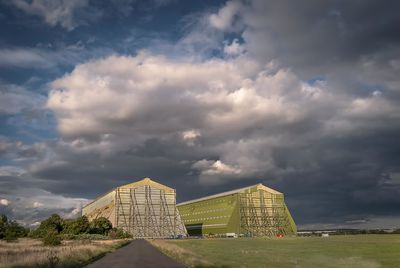 Built structure on landscape against cloudy sky