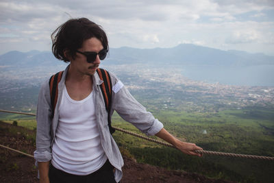 Young woman wearing sunglasses standing on mountain against sky