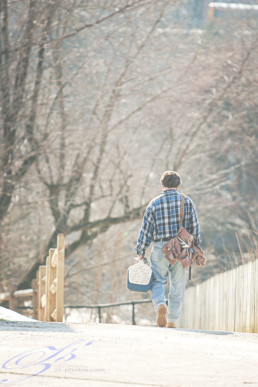 full length, rear view, lifestyles, leisure activity, men, tree, casual clothing, built structure, walking, architecture, day, outdoors, railing, standing, person, building exterior, holding, footpath