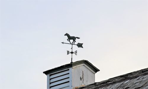 Low angle view of weather vane against building