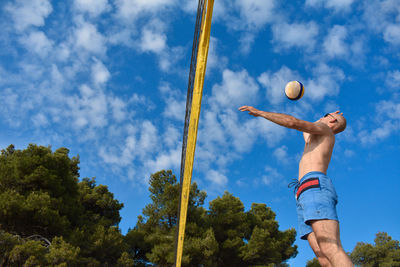 Shirtless man playing volleyball at beach