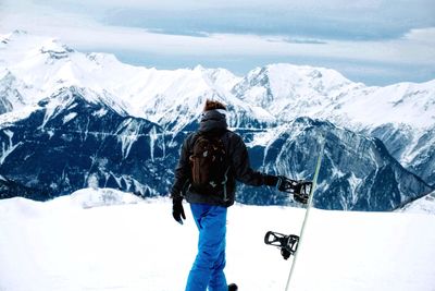 Rear view of man standing on snowcapped mountain