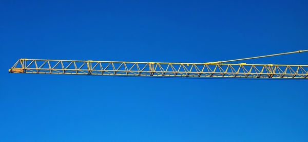 Low angle view of crane against clear blue sky