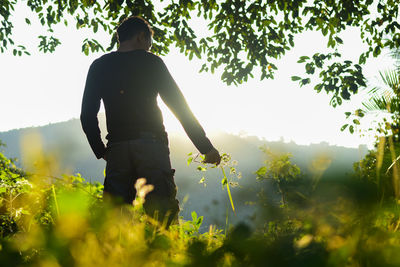 Rear view of man standing on field against sky