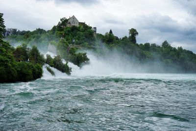 Scenic view of river and trees against cloudy sky