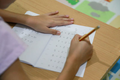 Close-up of girl writing on book at home