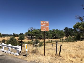 Information sign on field against clear blue sky