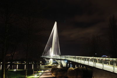 Illuminated bridge over river against sky at night