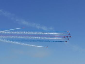 Low angle view of airplanes flying against blue sky