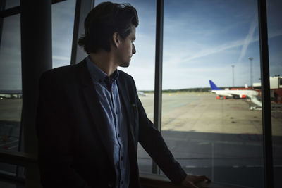 Businessman looking through glass window at airport