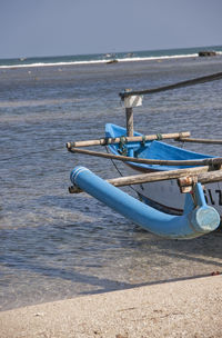 Boat moored on sea shore against sky