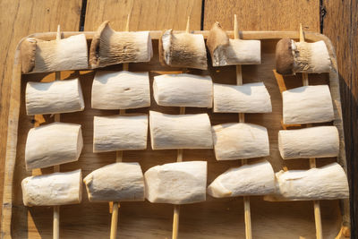 Eryngii mushroom on skewers placed in a wooden tray on the table