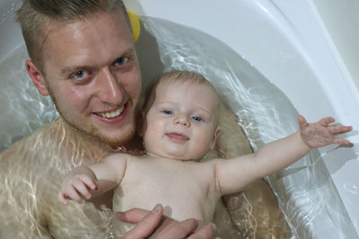 Portrait of cheerful father and son taking bath at bathroom
