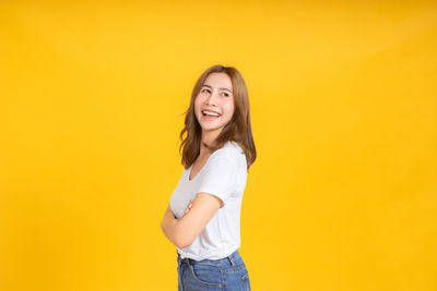 Portrait of a smiling young woman against yellow background