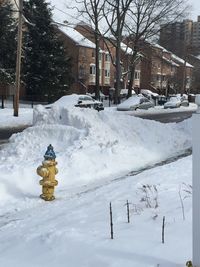 Snow covered field by building in city during winter