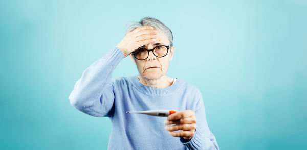 Young woman using mobile phone against blue background