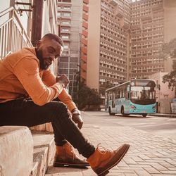 Side view of young man sitting on street