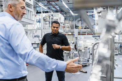 Engineer listening to businessman at automated industry