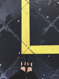 Low section of woman standing by yellow line on pavement