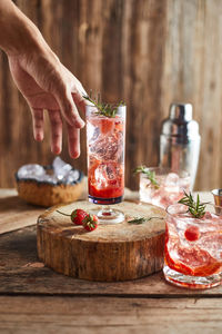 Cropped hand holding drink on table