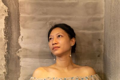 Portrait of young woman looking away against wall