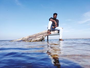 Man sitting in sea against sky