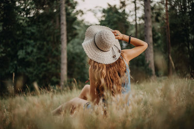 Rear view of woman wearing hat standing on field