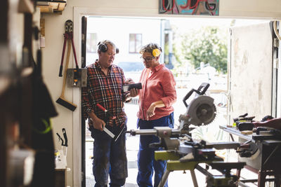 Senior couple using digital tablet while standing at workshop doorway