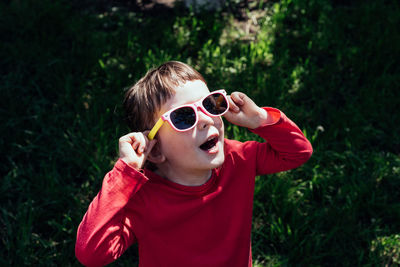 Happy child with open mouth looking at the sun in sunglasses. 