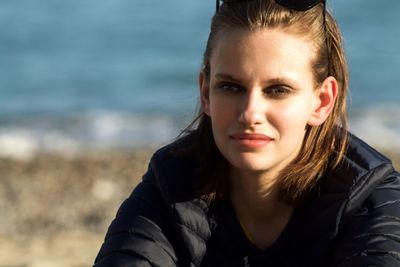 Close-up portrait of young woman against sea