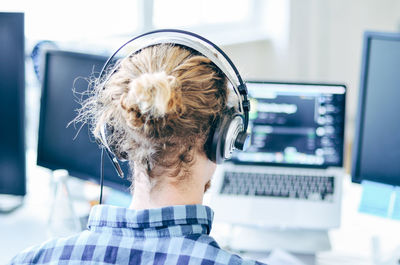 Rear view of woman sitting in front of laptop