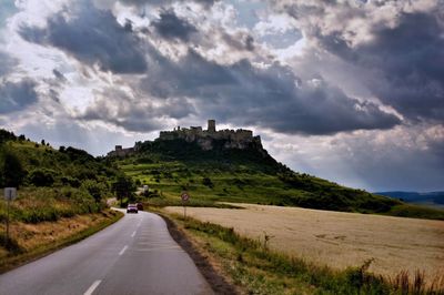 Road leading towards mountains against sky