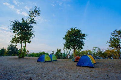 Tent on field against trees and blue sky