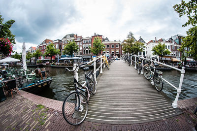 Footbridge over canal in city against sky