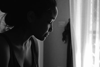 Side view of man looking through window at home