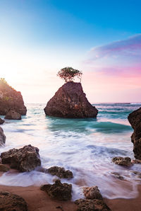 Rocks in sea against sky during sunset