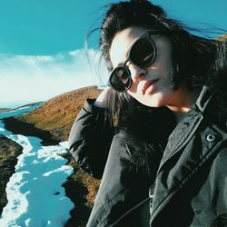Portrait of young woman with sunglasses against sky