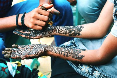 Cropped hand of artist applying henna tattoo on woman