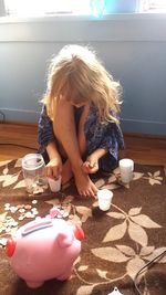 Girl counting coins while sitting on floor at home