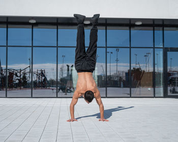 Shirtless young man exercising on footpath