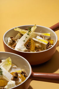 Close-up of one pot pasta with chicory, orange, goat cheese and candied walnuts in bowl on table