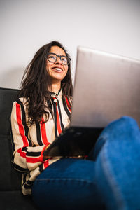 Smiling young woman using laptop while sitting at office