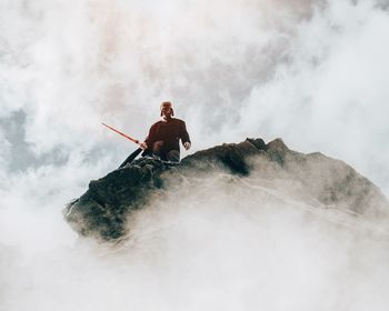 Woman standing on mountain against cloudy sky