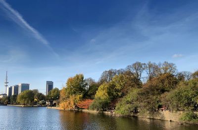 Scenic view of river by trees and buildings against sky