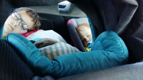 High angle view of boys sleeping in car