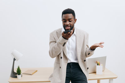 Portrait of young man standing against white background