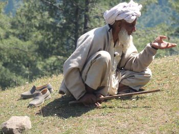 Man sitting with stick on grass